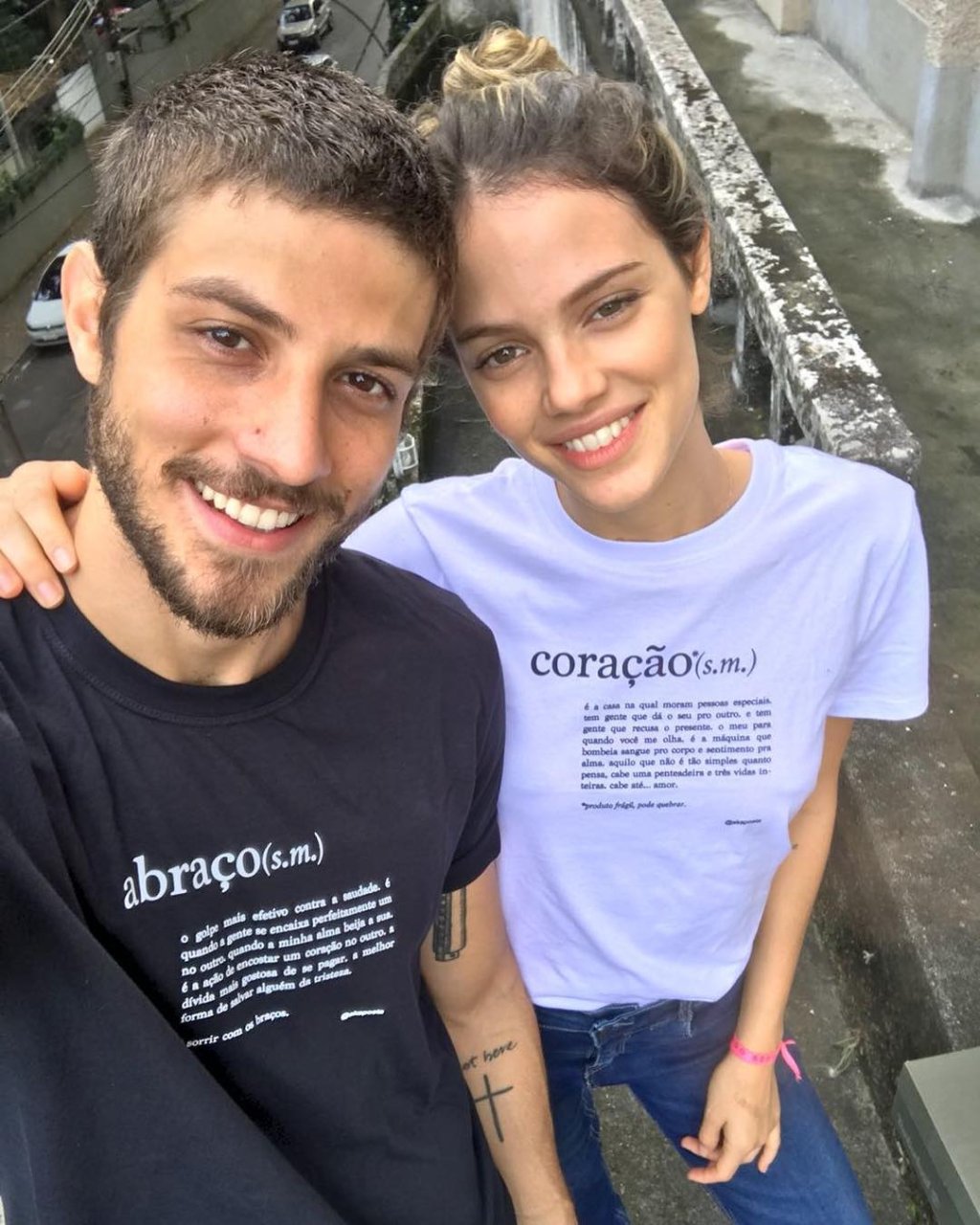 Selfie de Chay Suede e Laura Neiva; na foto os dois estão sorrindo para câmera com as cabeças encostadas e ela está com a mão em volta do pescoço do ator em um abraço; ele usa uma camiseta preta e ela uma branca