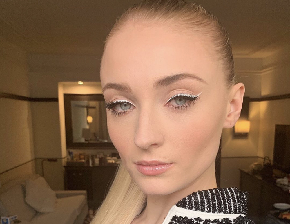 Sophie Turner com os cabelos presos em um rabo de cavalo e delineador branco.