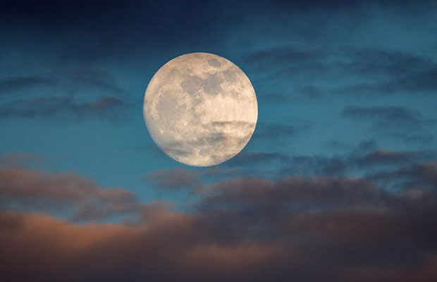 Céu azulado com uma lua cheia e nuvens ao seu redor