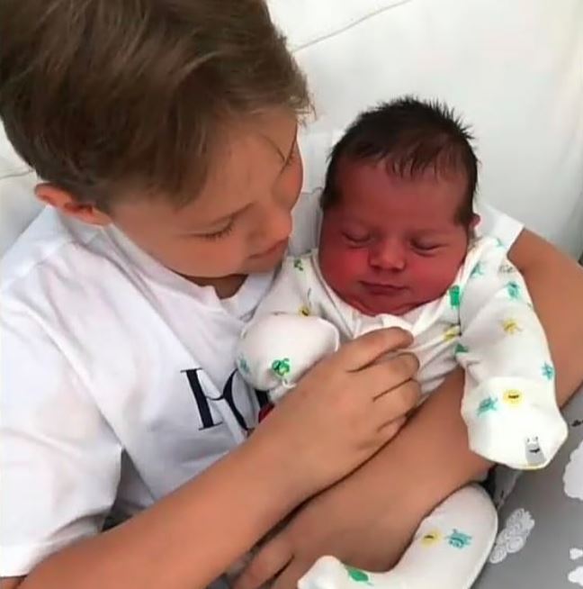 Davi Lucca segurando o irmão recém-nascido