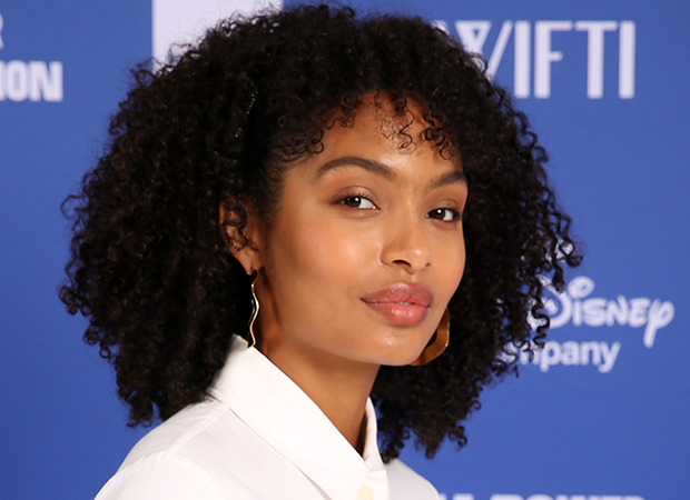 Yara Shahidi com expressão sorridente posando para foto com camisa branca.