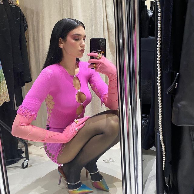 tendencia-polemica-recortes-dualipa Dua Lipa usando vestido rosa com recortes circulares na região do colo, dos seios e da barriga