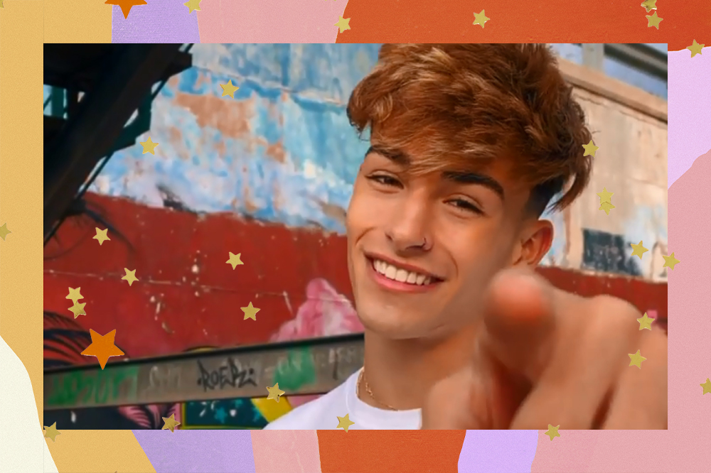 Alex, novo membro do Now United, sorrindo e apontando o dedo para a câmera