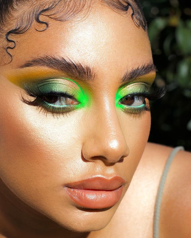 maquiagem-olho-verde-daiisycarters Garota usando maquiagem com diferentes tonalidades de verde nos olhos. A pele está bem iluminada, com bronzer, batom cor de boca e cílios postiços. Na foto, só dá para ver o rosto dela. Sua expressão é séria e ela olha para o lado.