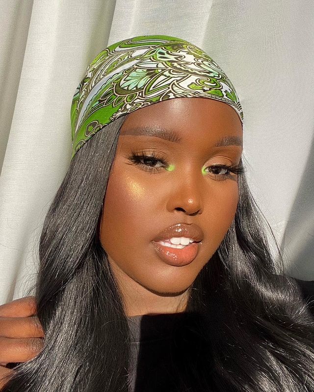 maquiagem-olho-verde-fatimacaser Garota usa sombra verde neon no canto interno dos olhos e um lenço verde na cabeça. Na foto, só dá para ver seu rosto. Seu cabelo é preto e ela está olhando para a câmera com a boca levemente aberta.