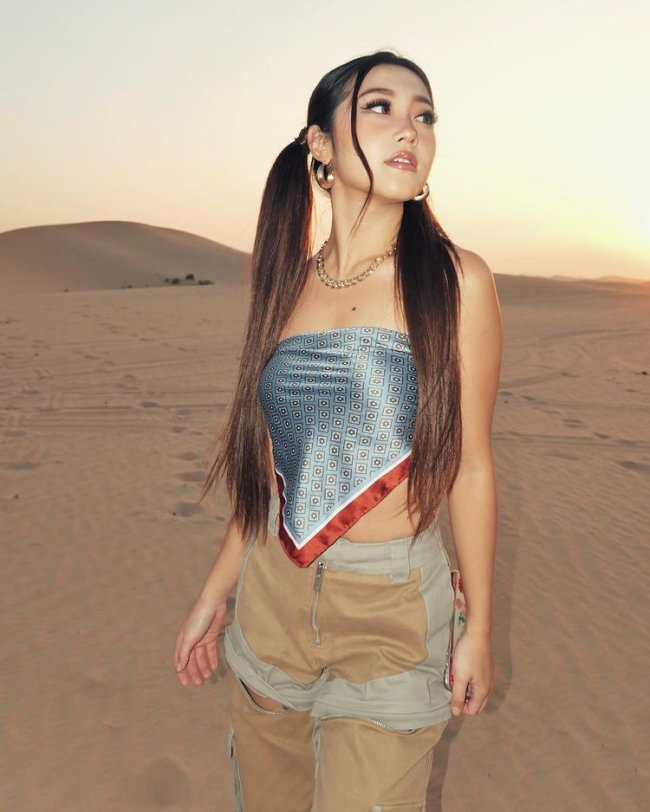 now united heyoon Heyoon do now united usando lenço como top, short, e cabelos amarrados em maria chiquinha posando para foto enquanto olha para o lado.