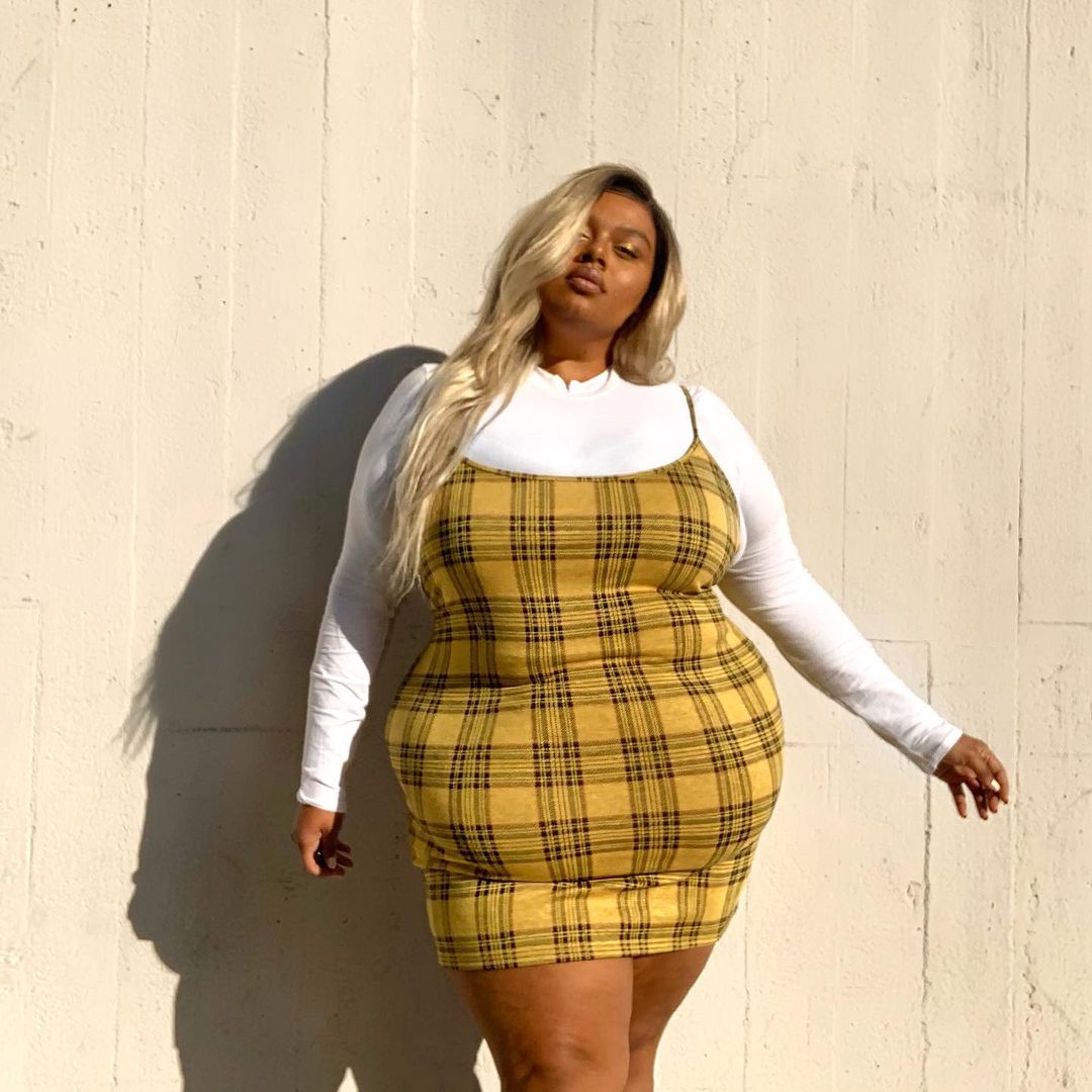 tendencias-outono-inverno-thestellawilliams Garota usando blusa de manga longa branca por baixo de vestido xadrez amarelo e preto de alcinha.