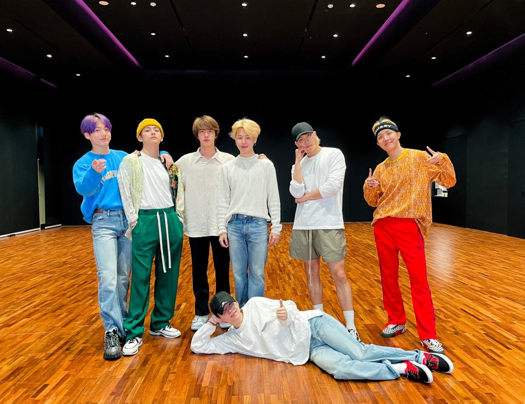 Os sete membros do BTS em foto de divulgação; seis deles estão em pé alinhados na horizontal enquanto um está deitado de lado no chão com a cabeça apoiada o braço; todos estão posando para câmera