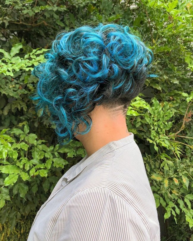 Jovem de costas com cabelo colorido azul, usando camisa branca.