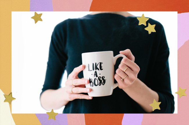 Mulher com anéis e camiseta preta segurando uma caneca branca com os dizeres: 