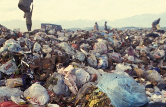 Coisas que você ainda usa, não são recicláveis e poluem o planeta por anos Imagem de um lixão a céu aberto; ao fundo, pessoas convivem no meio da montanha de lixo