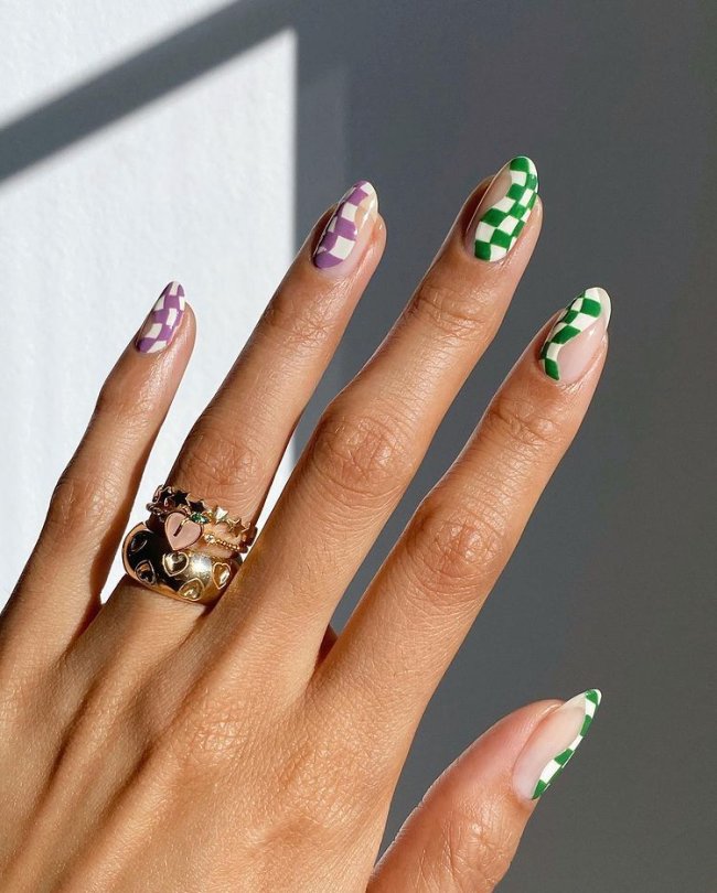 nail art xadrez Foto de uma mão com anéis no dedo anelar. As unhas estão com uma nail art ondulada na estampa xadrez.