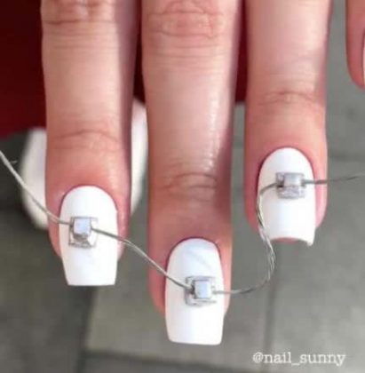 Foto com destaque nas unhas que estão com nail art inspirada em aparelho dentário