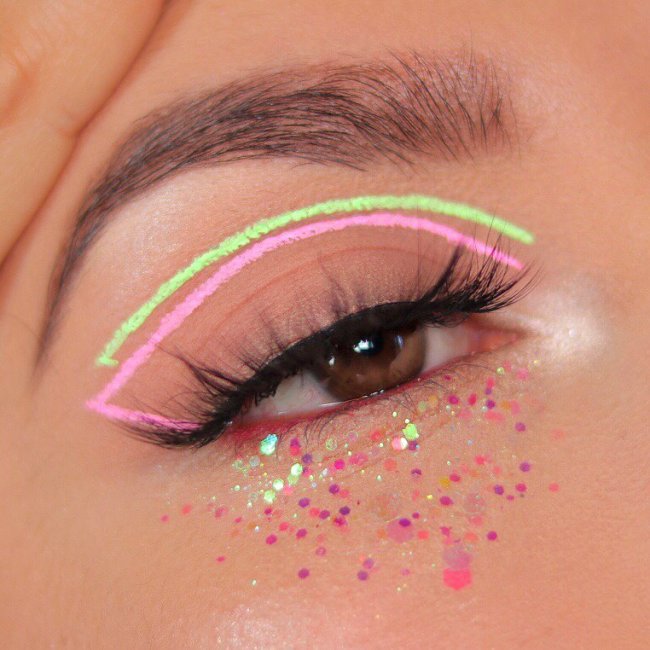 delineado gráfico verde e rosa Foto de um olho. Ele está com um delineado gráfico nos tons verde e rosa pastel, com glitter na parte inferior e cílios postiço.