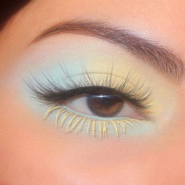 sombra em tons pastel Foto de um olho. Ele está com uma sombra azul e amarelo pastel, com cílios postiços e rímel amarelo nos cílios inferiores.