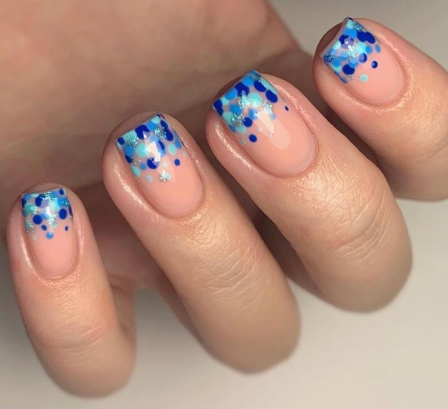 Foto com destaque nas unhas com nail art de bolinha, dessa vez com bolinhas em varios tons de azul na ponta da unha.