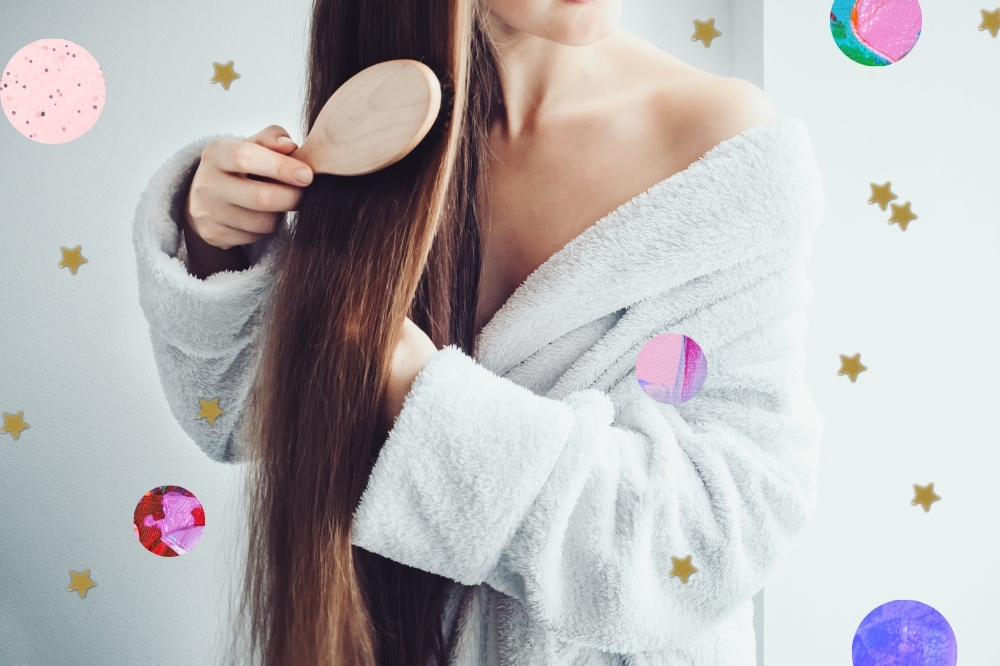 Jovem com roupão branco, penteando seu cabelo. Não conseguimos ver seu rosto.