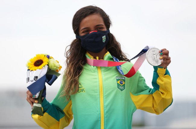 Rayssa Leal no pódio de Tóquio 2020, segundado sua medalha de prata e um buquê de girassóis