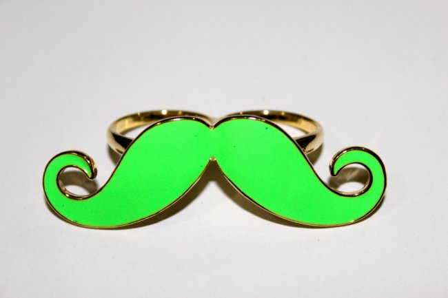anel-de-bigode-verde Foto de um anel verde neon com formato de bigode.