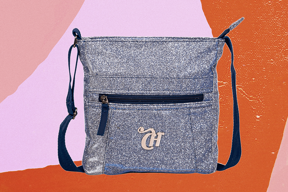 Bolsa transversal de glitter da CAPRICHO com a Sestini em fundo laranja e rosa