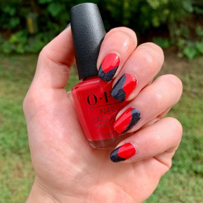 unha vermelha e preta Foto com foco nas mãos exibindo a nail art das unhas. No caso, unhas vermelhas com detalhes em preto.