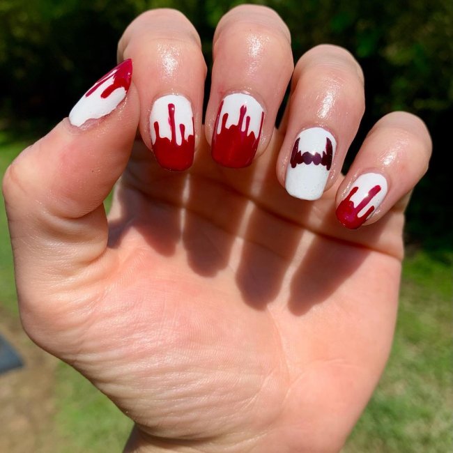 unha vermelha imitando sangue Foto com foco nas mãos exibindo a nail art das unhas. No caso, unhas brancas com detalhe de vermelho nas pontas.