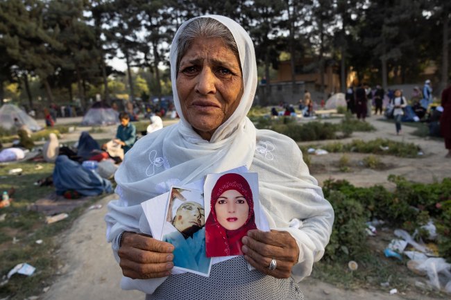 Uma senhora de 60 anos, vestindo um hijab branco e chorando, segura fotos de sua filha, que ela diz ter sido morta há um mês por membros do Talibã