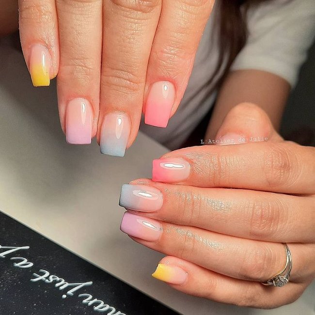 baby-boomer-colorida Foto de duas mãos com foco nas unhas decoradas no estilo baby boomer multicoloridas.