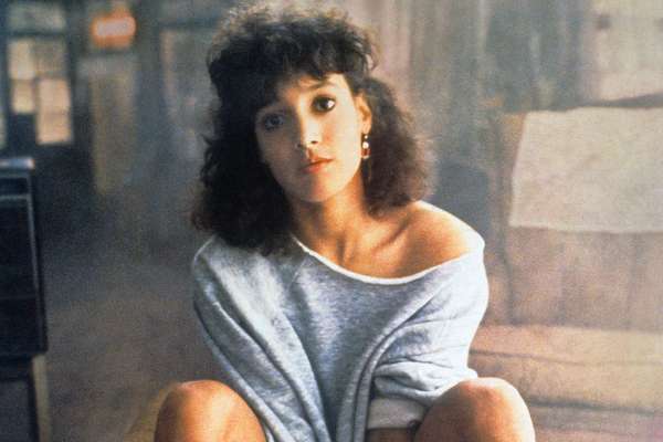 Personagem do filme Flashdance sentada com expressão séria