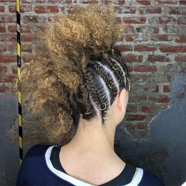 Penteado com moicano e tranças na lateral usando piercing.