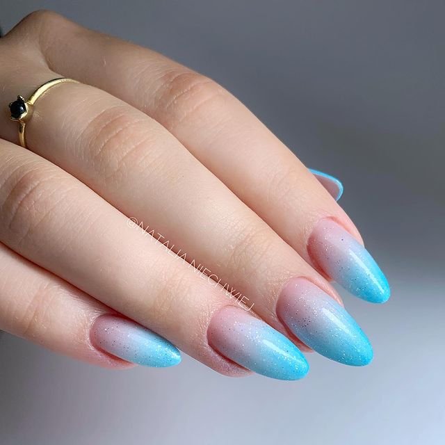 Foto de uma mão com foco nas unhas decoradas no estilo baby boomer em um tom de azul.