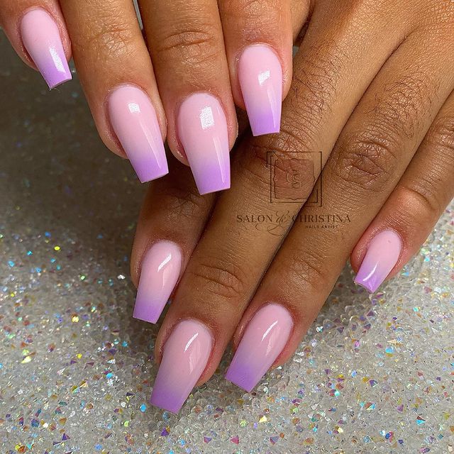 unhas-baby-boomer-rosa-lilas Foto de duas mãos com foco nas unhas decoradas no estilo baby boomer nos tons rosa e lilás.