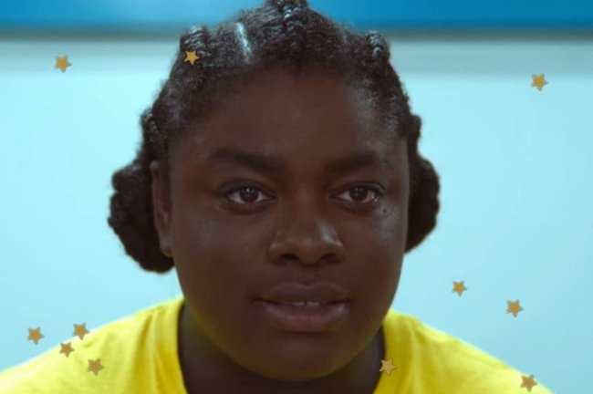 Space Buns Sex Education Personagem de Sex Education com space buns expressão séria e usando camiseta amarela.