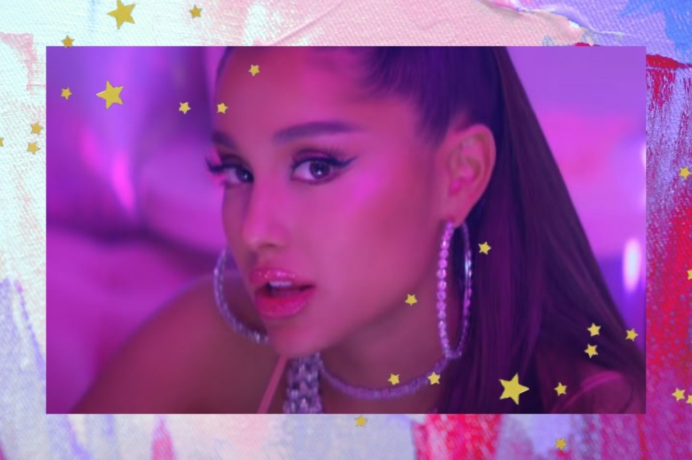 Montagem com o fundo rosa e roxo com detalhe de estrelinhas douradas com a foto de uma parte do clipe da Ariana Grande. Ela usa um brinco de argola grande, colar, rabo de cavalo e maquiagem com delineador e gloss.