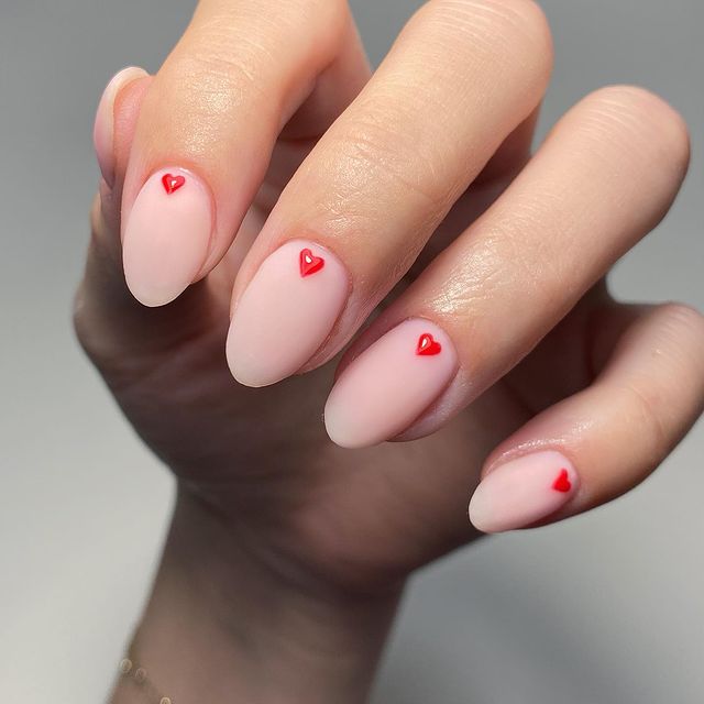 Foto com destaque nas unhas com desenho de pequenos corações.