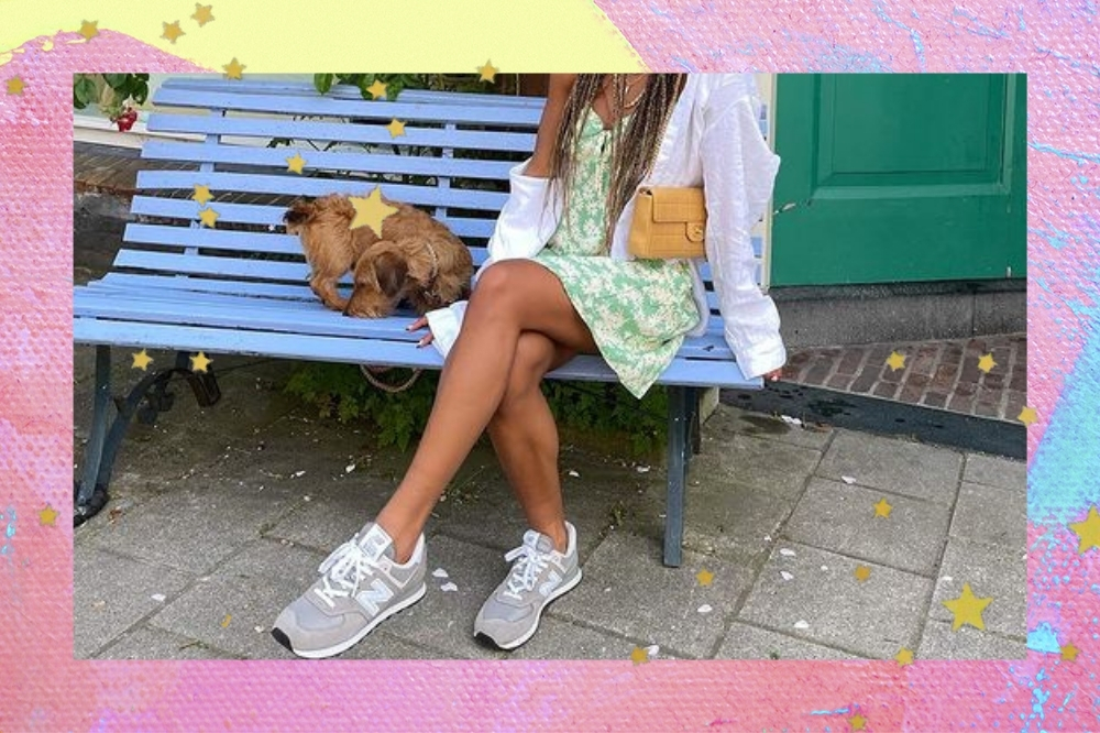 Foto de um mulher sentada em um banquinho com as bordas rosa com amarelo e detalhe de estrelinhas douradas. A mulher usa um vestido curto verde, camisa branca como sobreposição, bolsa laranja e tênis esportivo.