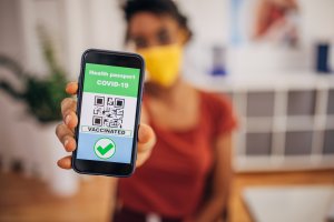 Enem 2021: atualidades que podem ser cobradas na prova e na redação Foto de uma mulher, com o rosto desfocado, exibindo seu passaporte da vacinação no celular