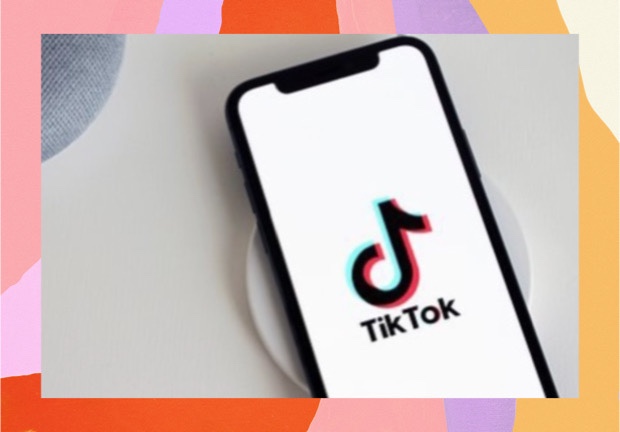 Imagem de um celular com a tela aberta no aplicativo TikTok, com moldura colorida de fundo.