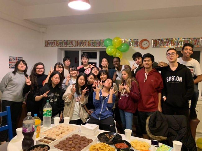 Foto de Marine, da Galera CH, durante intercâmbio. Está rolando uma festa de despedida dos alunos, com comes e bebes bem brasileiros, e balões verde e amarelo