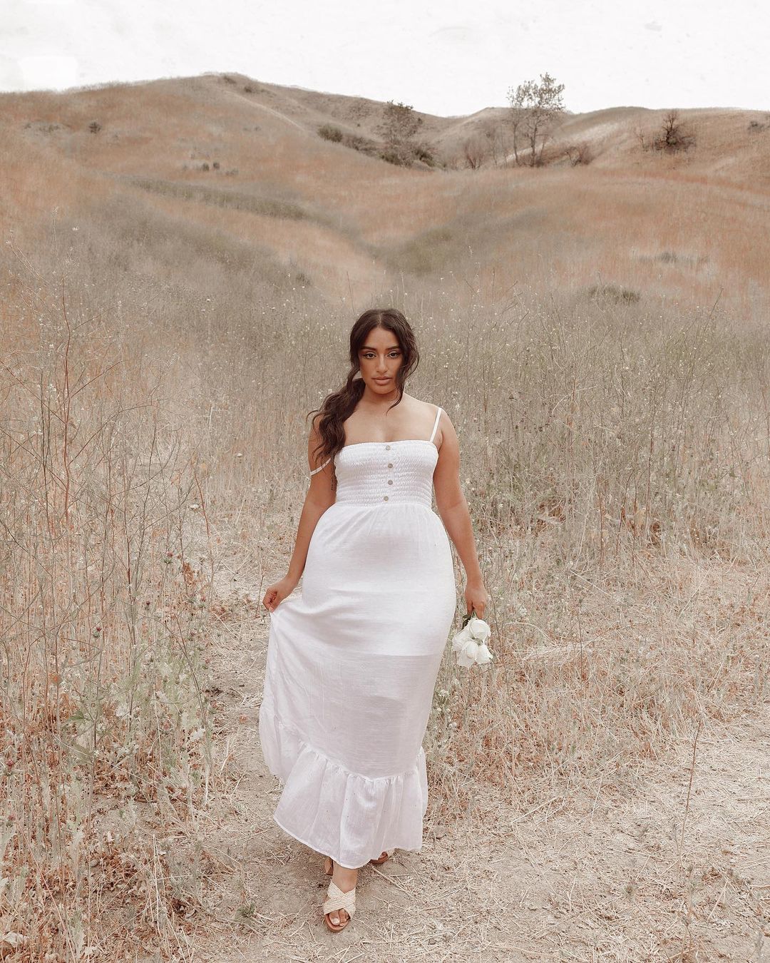 look-vestido-branco-_jasminvanessa Garota usando vestido branco longo de alcinha com cabelo preso em rabo baixo em paisagem de campo