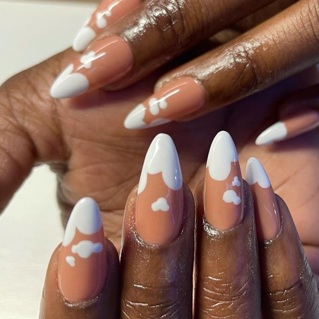 nail-art-nuvens Foto de mãos com o esmalte nude e decoração de nuvens brancas.