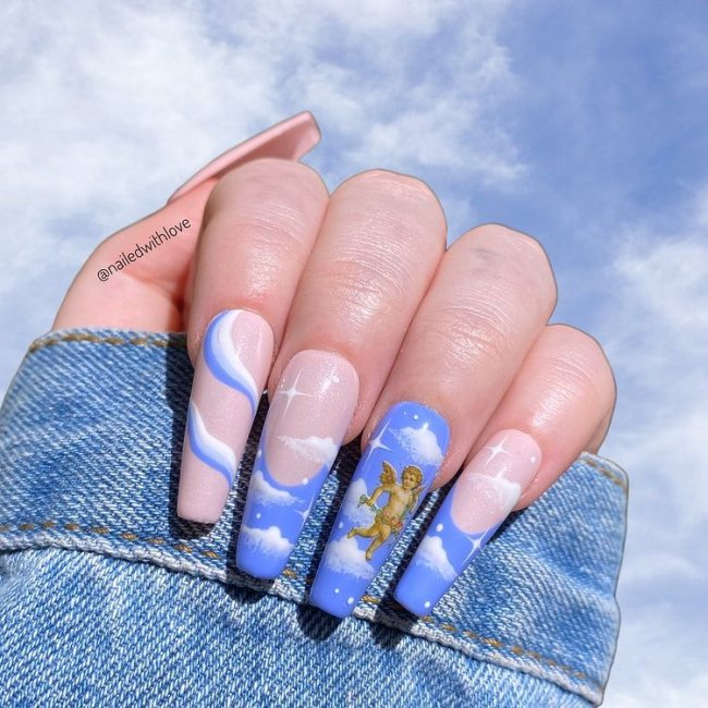 unhas-com-decoracao-de-nuvens Foto de uma mão com o fundo de nuvens. As unhas dessa mão estão decoradas com esmalte azul e detalhes de nuvens e anjinhos.
