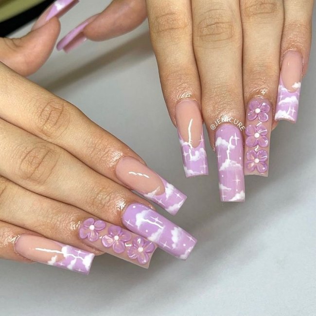 unhas-lilas-com-nuvens Unhas com esmalte lilás e decoração de nuvens brancas.