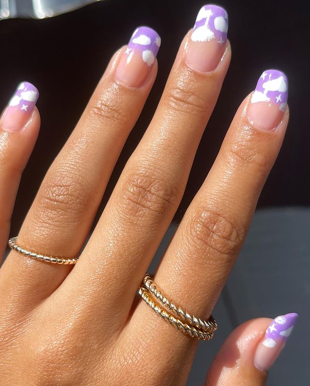 unhas-roxos-com-decoracao-de-nuvens Unhas com esmalte roxo nas pontas e decoração de nuvens brancas.