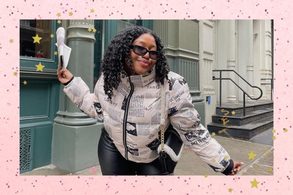 Montagem com o fundo rosa e detalhe de estrelinhas douradas nas bordas com a foto de uma mulher no centro. Na foto ela está em uma calçada, usa calça preta, casaco puffer com estampa de jornal e bolsa preta com detalhes em pelúcia branca. Ela usa um óculos de sol, segura um jornal com a mão direita, olha para a câmera e sorri levemente.