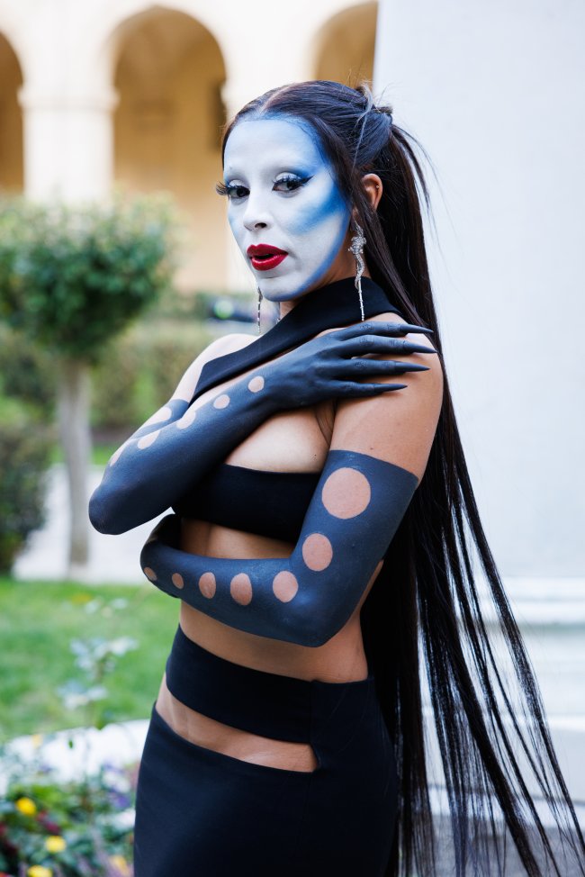 maquiagem-artistica-semana-de-moda-paris-doja-cat Foto da cantora Doja Cat na Semana de Moda de Paris com uma maquiagem artística azul. Ela olha para a câmera e não sorri.