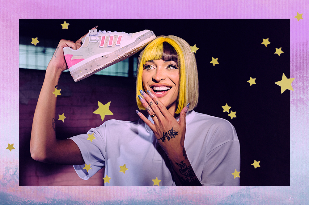 Montagem em fundo degradê lilás e azul com foto da Pabllo Vittar fazendo expressão de surpresa enquanto segura seu tênis em parceria com a Adidas