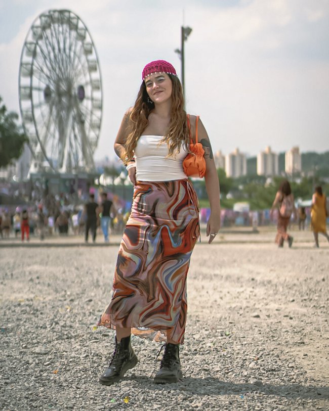 look-saia-estampa-psicodelica-lollapalooza Foto de uma mulher no Lollapalooza 2023 com look com saia longa de estampa psicodélica, top branco e lenço na cabeça.