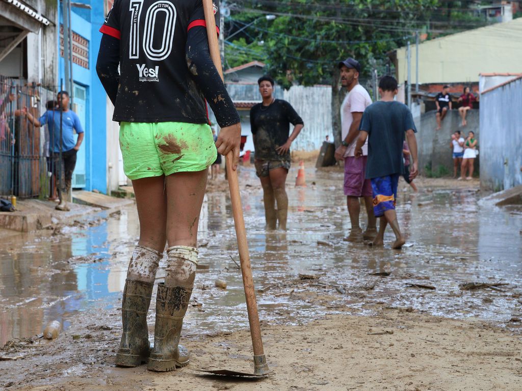 Pessoas com bota e enxada retirando lama