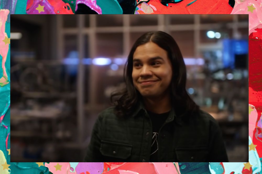 Cisco, personagem da série The Flash, sorrindo em cena da 7ª temporada da produção; a margem é uma textura nas cores lilás, verde, rosa, vermelho, roxo e preto; estrelas amarelas decoram a imagem